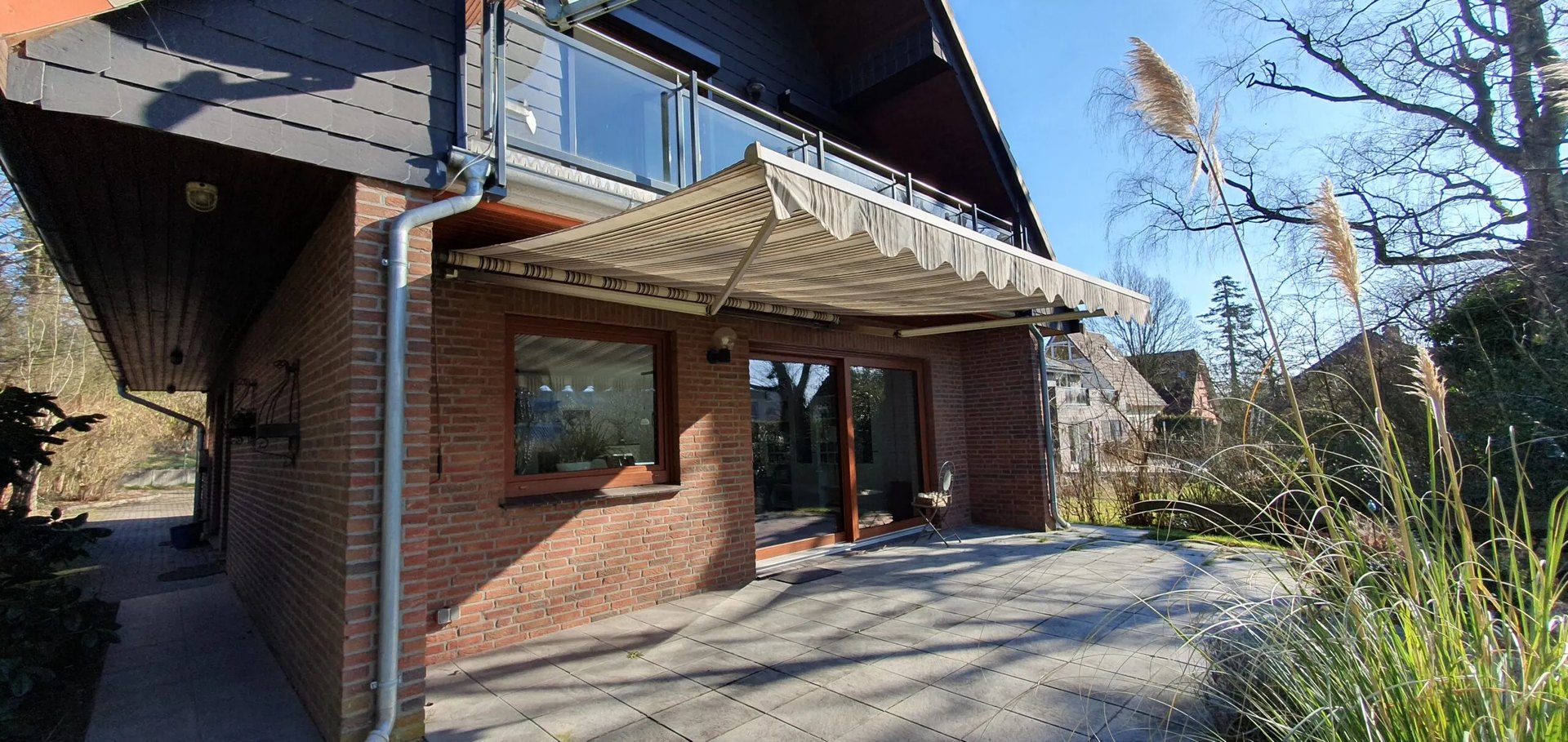 Backsteinhaus mit ausgefahrener, gestreifter Markise